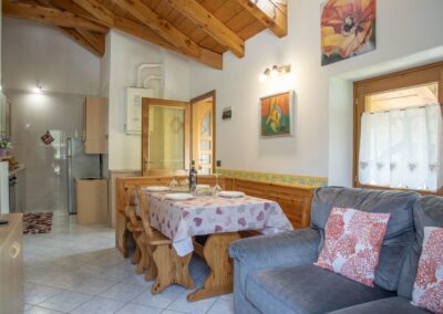 Soggiorno dell'appartamento Cevedale con tavolo apparecchiato, divano e soffitto in travi di legno