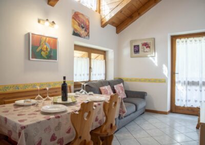 Zona pranzo del Cevedale sotto il tetto in legno, con tavolo apparecchiato e divano