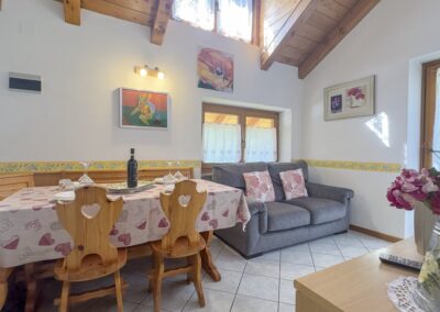 Tavolo da pranzo con sedie in legno intagliato e divano nel soggiorno del Cevedale