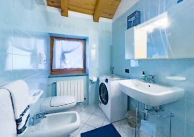 Secondo bagno del Cevedale, con pareti azzurre, lavatrice e lavabo