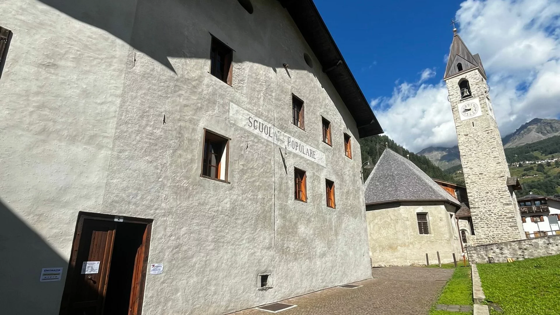 palazzo-migazzi Palazzo Migazzi a Cogolo di Peio, con la scritta Scuola Popolare sulla facciata e il campanile accanto