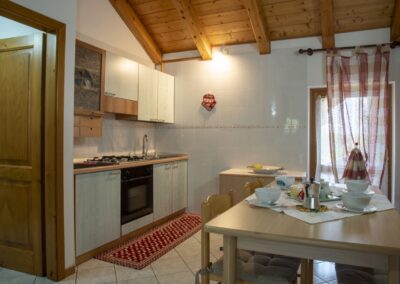 Cucina e zona pranzo del Presanella sotto il tetto in travi di legno