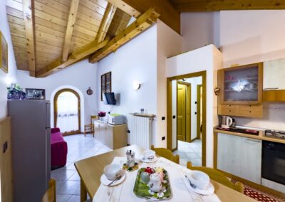 Zona giorno del Presanella con cucina, tavolo apparecchiato e poltrona