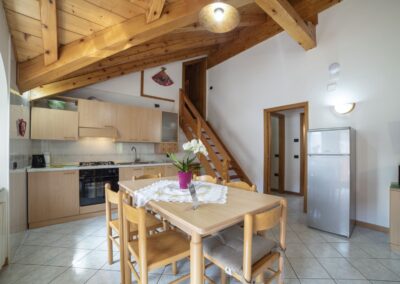 Cucina e tavolo da pranzo del Vioz, con scala interna in legno