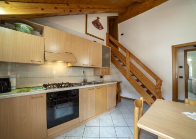 Cucina del Vioz con piano cottura, forno e scala che sale al piano superiore