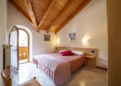 Camera matrimoniale del Vioz con finestra ad arco e soffitto in legno